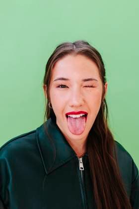 Playful portrait of woman winking and sticking out tongue against green model released, Symbolfoto, FOMF00496