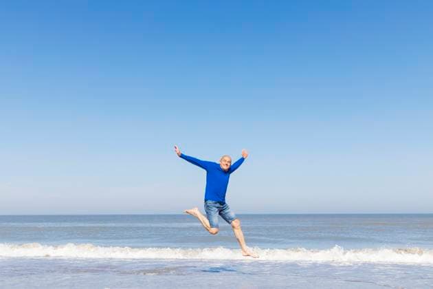 Man jumping for joy on the beach with blue sky and sea model released, Symbolfoto, GWF08396