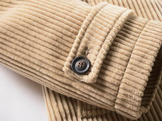 Close-up of a beige ribbed corduroy fabric with a black button on a sleeve. mlma00597 Copyright: xConnectxImagesx
