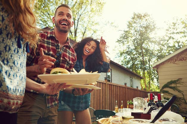 Friends, laugh and lunch at backyard party, excited and reunion with plate at new year cookout. People, group and smile with low angle, hungry and bonding at social gathering on holiday in summer. model released property released Copyright: xx
