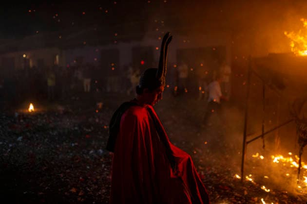 December 8, 2025, Antigua Guatemala, Sacatepequez, Guatemala: A man dressed as a devil walks past the bonfire during the Burning of the Devil in Antigua Guatemala, on the eve of the celebration of the Virgin of the Immaculate Conception, festivities that mark the beginning of Christmas in Guatemala. Antigua Guatemala Guatemala - ZUMAs296 20251208_znp_s296_010 Copyright: xLuisxSotox