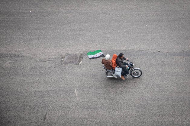 News Bilder des Tages December 8, 2025, Homs, Syria: A passenger on a motorbike waves a Syrian flag in central Homs. Celebrations were held in Homs on the eve of the first anniversary of the fall of Bashar al-Assad s regime. Homs Syria - ZUMAs197 20251208_aaa_s197_032 Copyright: xSallyxHaydenx