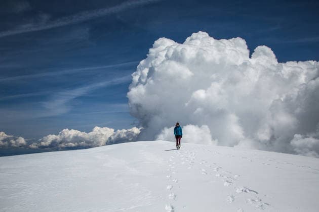 A woman walks atop a snowy mountain dome with big clouds in background Trout Lake, Washington, United States CR_AXTH251205-1863371-01 ,model released, Symbolfoto