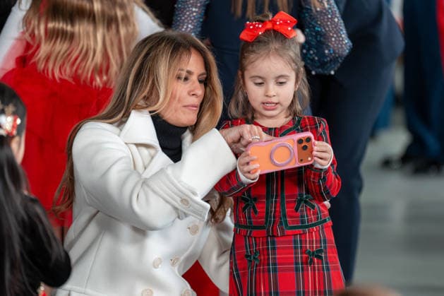December 8, 2025, Quantico, Virginia, USA: First Lady MELANIA TRUMP points to something on a phone a young girl is holding before they take a selfie together at a Toys for Tots event at Marine Corps Base Quantico. Quantico USA - ZUMAs365 20251208_znp_s365_001 Copyright: xJoeyxSussmanx