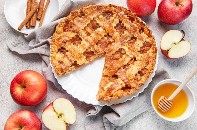 Homemade apple pie with a missing slice, cinnamon sticks, honey, and fresh red apples on a gray background Model Released OlenaRudo_ID32506_1107586_031 Copyright: xOlenaxRudox