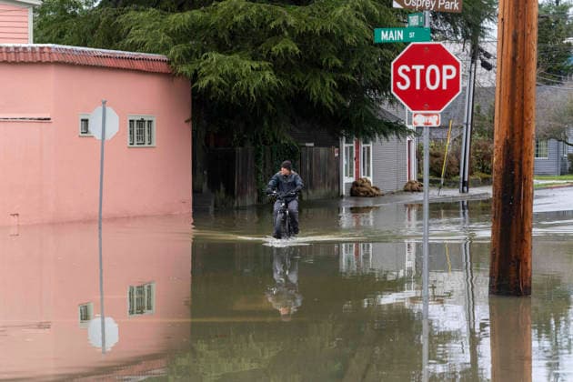 December 11, 2025, Sultana, Washington, USA: A man rides a bicycle through flood waters from the Skykomish River inundating a portion of downtown Sultana, Washington, USA, on Thu., Dec. 11, 2025, after a trio of atmospheric rivers drenched the region. Forecasts said that many rivers in the Pacific Northwest would reach catastrophic flood levels and the governor has declared a state of emergency. Sultana USA - ZUMAb344 20251211_znp_b344_004 Copyright: xM.xScottxBrauerx