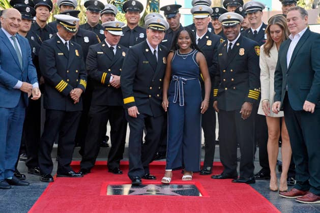 Eniola Taiwo (R) and LAFD Chief Jaime E. Moore participate in an unveiling ceremony honoring the Los Angeles Fire Department with an Award of Excellence star adjacent to the Hollywood Walk of Fame in Los Angeles on Tuesday, December 2, 2025. Taiwo, 14, wrote a letter to the Hollywood Chamber of Commerce suggesting that firefighters who battled the deadly January fires were worthy of a star on the Hollywood Walk of Fame. The letter precipitated the tribute.  LAP2025121205 JIMxRUYMEN