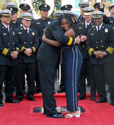 Eniola Taiwo (R) and LAFD Chief Jaime E. Moore participate in an unveiling ceremony honoring the Los Angeles Fire Department with an Award of Excellence star adjacent to the Hollywood Walk of Fame in Los Angeles on Tuesday, December 2, 2025. Taiwo, 14, wrote a letter to the Hollywood Chamber of Commerce suggesting that firefighters who battled the deadly January fires were worthy of a star on the Hollywood Walk of Fame. The letter precipitated the tribute.  LAP2025121207 JIMxRUYMEN