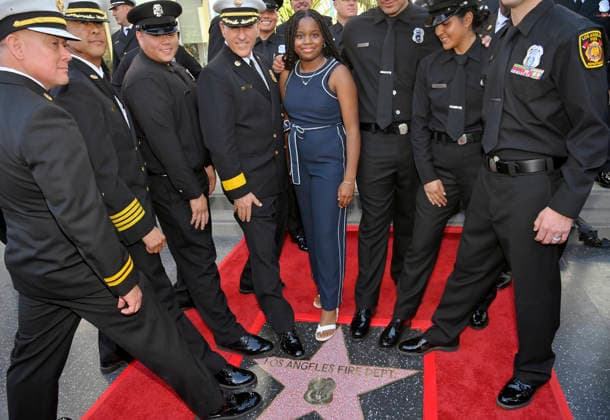 Eniola Taiwo (R) and LAFD Chief Jaime E. Moore (4th-R) participate in an unveiling ceremony honoring the Los Angeles Fire Department with an Award of Excellence star adjacent to the Hollywood Walk of Fame in Los Angeles on Tuesday, December 2, 2025. Taiwo, 14, wrote a letter to the Hollywood Chamber of Commerce suggesting that firefighters who battled the deadly January fires were worthy of a star on the Hollywood Walk of Fame. The letter precipitated the tribute.  LAP2025121210 JIMxRUYMEN