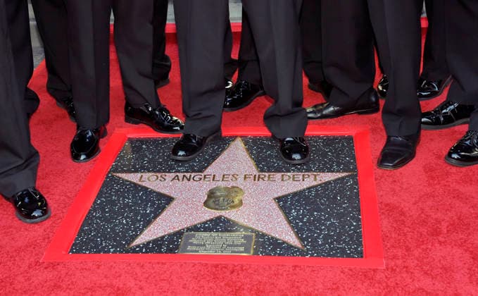 Firefighters participate in an unveiling ceremony honoring the Los Angeles Fire Department with an Award of Excellence star adjacent to the Hollywood Walk of Fame in Los Angeles on Tuesday, December 2, 2025. EniolaTaiwo, 14, wrote a letter to the Hollywood Chamber of Commerce suggesting that firefighters who battled the deadly January fires were worthy of a star on the Hollywood Walk of Fame. The letter precipitated the tribute.  LAP2025121221 JIMxRUYMEN