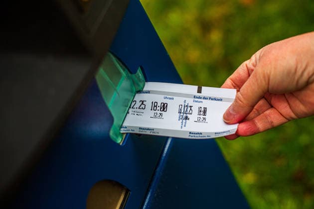 Eine Frau zieht einen Parkschein an einem Parkautomaten. Parkschein *** A woman takes a parking ticket from a parking machine Parking ticket