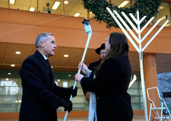 December 14, 2025, Ottawa, On, CAN: Prime Minister Mark Carney passes a torch to Olivia Mellcovsky for her to light the menorah at City Hall in Ottawa to celebrate Hanukkah, in the aftermath of a deadly shooting at a Jewish event in Sydney, Australia, on Sunday, Dec. 14, 2025. Ottawa CAN  - ZUMAc35_ 20251214_zaf_c35_002 Copyright: xJustinxTangx