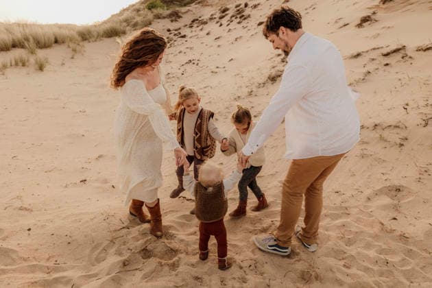 Young family dancing together along a dune ridge at sunset Amsterdam, North Holland, Netherlands CR_RTBZ2512154F-1910441-01 ,model released, Symbolfoto
