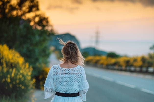 A woman is walking down a road with a yellow bush in the background A woman is walking down a road with a yellow bush in the background. The sky is orange and the sun is setting, model released, , 61517538.jpg RECORD DATE NOT STATED