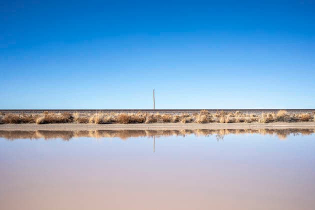 Empty landscape blue sky train tracks reflection in puddle Lordsburg, New Mexico, United States CR_MALI251221C-1906720-01