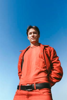 Low angle view of young man in red clothing posing under clear blue sky Sweden, Stockholm, model released Copyright: xMaskotx , MA122063 MA122063