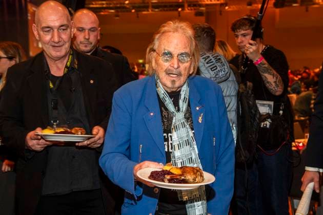 abb Frank Zander as celebrity waiter serving plates with Gaensekeuele red cabbage and dumplings at the 31 Frank Zander Christmas Party Christmas Dinner for Homeless and Needy People 2025 at Estrel Convention Center on December 22, 2025 in Berlin Berlin Germany