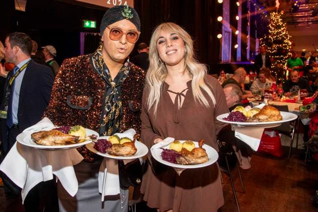 abb Julian F M Stoeckel and Annemarie Eilfeld as celebrity waiters serving plates with Gaensekeuele red cabbage and dumplings at the 31 Frank Zander Christmas Party Christmas Dinner for Homeless and Needy People 2025 at Estrel Convention Center on December 22, 2025 in Berlin Berlin Germany