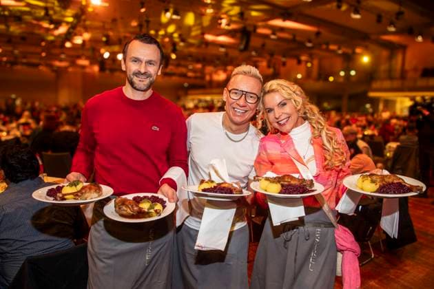 abb: David Biethig, Sascha Lauterbach und Victoria Herrmann als Promi Kellner beim Servieren von Teller mit Gaensekeuele Rotkohl und Kloesse bei der 31. Frank Zander Weihnachtsfeier Weihnachtsessen fuer Obdachlose und Beduerftige Menschen 2025 im Estrel Convention Center am 22.12.2025 in Berlin Berlin Deutschland