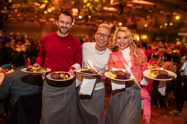 abb: David Biethig, Sascha Lauterbach und Victoria Herrmann als Promi Kellner beim Servieren von Teller mit Gaensekeuele Rotkohl und Kloesse bei der 31. Frank Zander Weihnachtsfeier Weihnachtsessen fuer Obdachlose und Beduerftige Menschen 2025 im Estrel Convention Center am 22.12.2025 in Berlin Berlin Deutschland