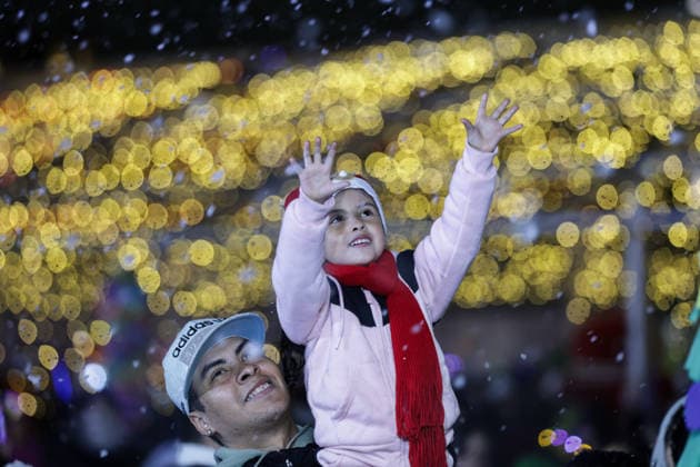 (251223) -- MEXICO CITY, Dec. 23, 2025 -- A child plays with artificial snow during a winter lights festival at the Zocalo square in Mexico City, Mexico, Dec. 22, 2025. A winter lights festival is held here to welcome the arrival of 2026. ) MEXICO-MEXICO CITY-WINTER LIGHTS FESTIVAL FranciscoxCanedo 