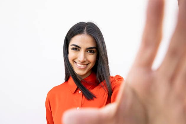 Confident woman in orange shirt smiling and looking at camera against white wall model released, Symbolfoto, LMCF02487