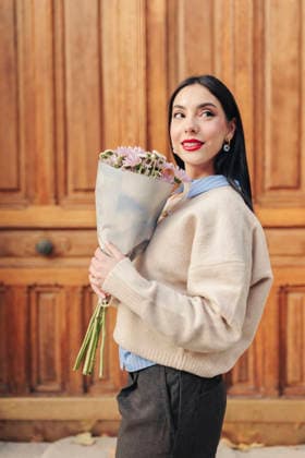 Smiling woman holding flower bouquet outdoors in front of wooden door model released, Symbolfoto, FOMF00621