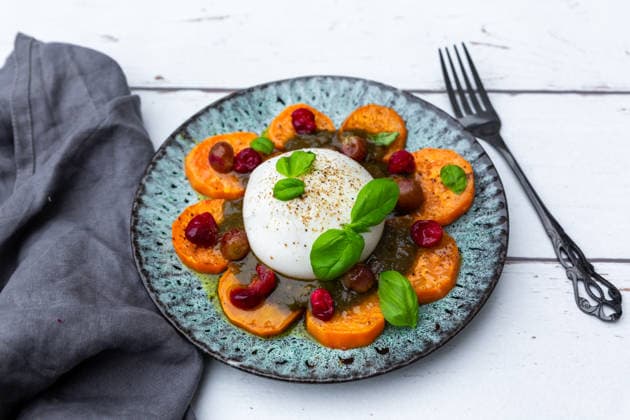 Burrata with sweet potato, pesto, cranberries, grapes, and basil on plate, SARF04689