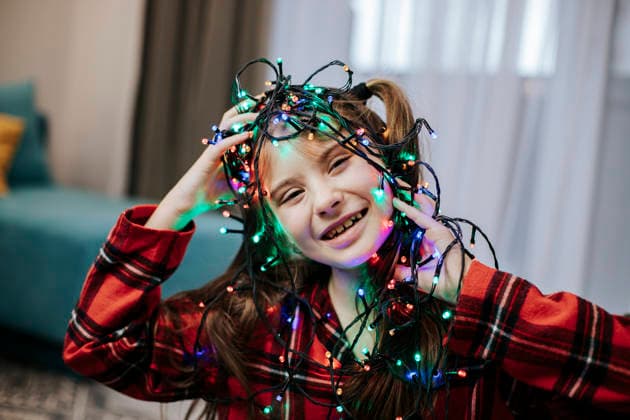 Child smiling in plaid sweater playing with christmas lights indoors model released, Symbolfoto property released, HDF00236
