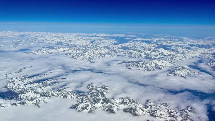 Creative Highlights World Experience the breathtaking aerial view of snowcapped mountains against a clear blue sky Stunning aerial footage showcases breathtaking snowcovered mountains contrasted against a bright blue sky, 96645686.jpg RECORD DATE NOT STATED