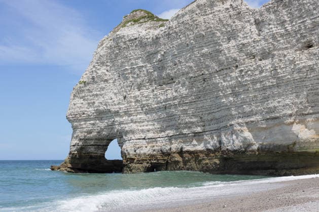 Creative Highlights World Beautiful view of a natural arch on a pebble beach in Etretat. Beautiful bottom side view from shore of the famous natural arch in the North Sea during low tide on a sunny summer day in Etretat, Normandy, France. Concept of beautiful natural backgrounds and wallpapers., 96812632.jpg RECORD DATE NOT STATED