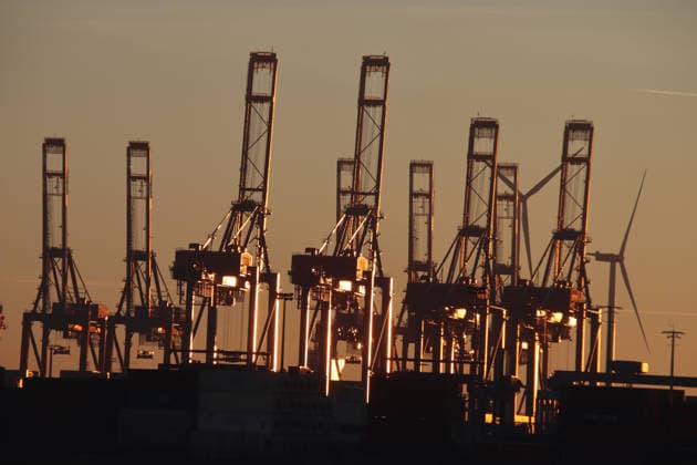 Container gantry cranes in the port of Hamburg reflect the light of the setting sun