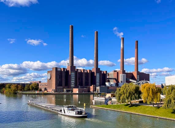 **Wolfsburg, Deutschland, Europa.** Industrieanlage des Volkswagen Kraftwerks am Mittellandkanal mit markanten Backsteingebäuden und mehreren hohen Schornsteinen. Im Vordergrund ein Frachtschiff auf dem Kanal, Uferbereich mit GrÃ NFL, American Football Herren, USA chen und Bäumen. Klarer Himmel, Tageslicht, ruhige Wasseroberfläche. Weitwinkel-Außenaufnahme, frontale Perspektive. Schlagworte: Industrie, Energie, Wirtschaft, Infrastruktur, Umwelt, Schifffahrt, Verkehr, Volkswagen, Deutschland, News, Gesellschaft, Symbolfoto. *** Wolfsburg, Germany, Europe Industrial plant of the Volkswagen power station on the Mittelland Canal with striking brick buildings and several high chimneys In the foreground a cargo ship on the canal, shore area with Copyright: xIMAGO AymanxAlahmedx