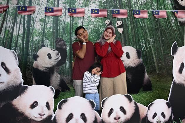 (260110) -- KUALA LUMPUR, Jan. 10, 2026 -- A family poses for photos with panda-themed decorations at Zoo Negara in Selangor, Malaysia, on Jan. 10, 2026. China s giant pandas Chenxing and Xiaoyue, currently on loan to Malaysia, officially met the public here on Saturday. TO GO WITH New giant panda couple makes public debut in Malaysia ) MALAYSIA-KUALA LUMPUR-GIANT PANDAS-PUBLIC DEBUT ChengxYiheng 