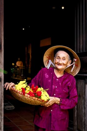 Elderly Vietnamese woman with flowers H?i An, Qu?ng Nam, Vietnam CR_ROMO260110-1922039-01 ,model released, Symbolfoto