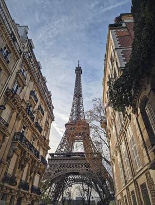 Niedriger Blick auf den Eiffelturm, eingerahmt von eleganten Pariser Wohnhäusern. Das komplizierte Eisengitterdenkmal thront über Fassaden im klassischen Haussmann Stil mit verzierten Balkonen Low-angle view of the Eiffel Tower framed by elegant parisian residential buildings. The intricate iron lattice monument towering over classic Haussmann style facades with ornate balconies Copyright: imageBROKER PsychoShadow ibxaiu16172015.jpg