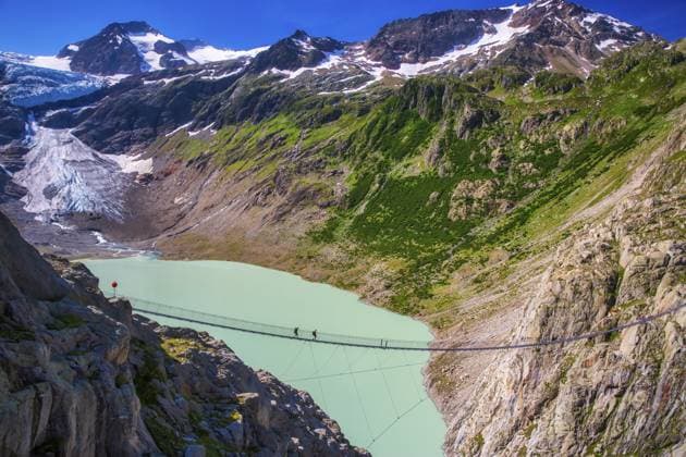 Triftbrücke, eine Fußgängerhängebrücke, die als Ersatz für einen durch den Gletscherschuss zerstörten Wanderweg gebaut wurde. Sie befindet sich in der Nähe des Triftgletschers, Klimawandel, globale Erwärmung, Gadmen, Kanton Bern, Schweiz Trift Footbridge, a pedestrian suspension bridge built to replace a hiking path destroyed by glacial retreat, located near the Trift Glacier, Climate Change, Global warming, Gadmen, Canton of Bern, Switzerland Copyright: imageBROKER ALESSANDRAxMENICONZI iblamm16283175.jpg