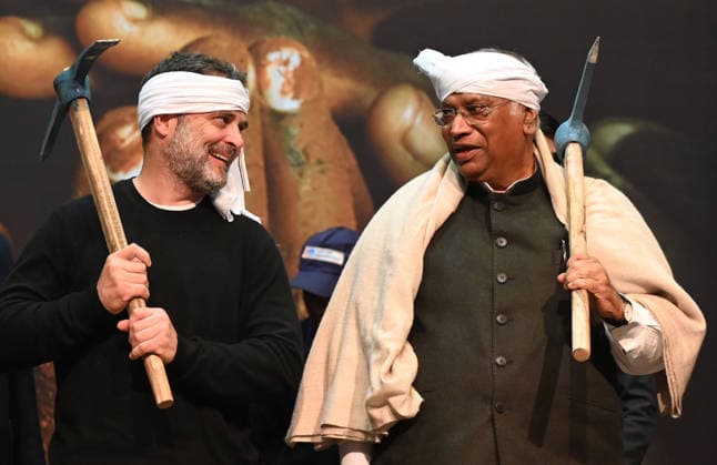 NEW DELHI, INDIA - JANUARY 22: Congress President Mallikarjun Kharge and Leader of Opposition Rahul Gandhi symbolically raise mattock picks (pickaxes) on their shoulders to express solidarity with rural laborers during the National MGNREGA Workers™ Convention at Jawahar Bhawan on January 22, 2026 in New Delhi, India. The convention was organized to mobilize resistance against the Viksit Bharat - Guarantee for Rozgar and Ajeevika Mission (Gramin) Act, which replaced MGNREGA in late 2025. (Photo by Sonu Mehta Hindustan Times) Congress President Mallikarjun Kharge And Leader Of Opposition Rahul Gandhi Address National MGNREGA Workers Convention In Delhi