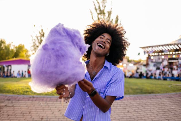 Cheerful young man holding cotton candy and enjoying in amusement park model released, Symbolfoto, ALZF00805