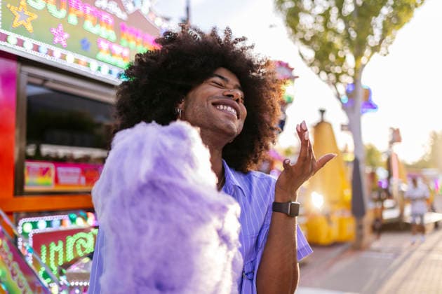 Happy young Afro man with cotton candy at amusement park model released, Symbolfoto, ALZF00807