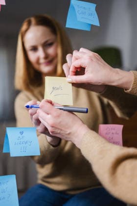 Woman writing positive affirmations on sticky notes in front of mirror model released, Symbolfoto property released, IGEF00611