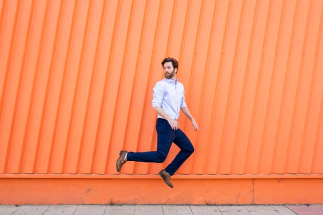 Business man jumping in front of orange wall outdoors model released, Symbolfoto, LMCF02592