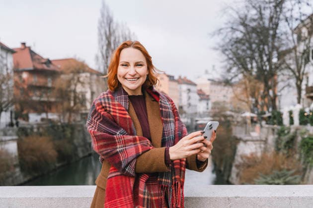 Smiling woman with smartphone on urban bridge with city in background model released, Symbolfoto, NDEF03104