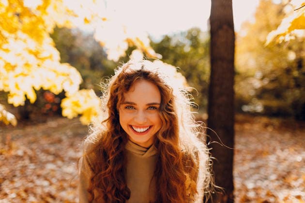 Lächelnde junge Frau genießt das Herbstwetter im Wald mit den gelben Blättern bei Sonnenuntergang. Smiling young woman enjoys the autumn weather in the forest with the yellow leaves at sunset (License=RM) ,model released, Symbolfoto Copyright: xZoonar.com Maxx4ex 24520742 ,model released, Symbolfoto ,property released