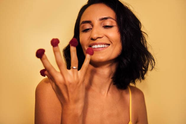 Frau mit dunklem Haar, die spielerisch ihre mit Himbeeren geschmückten Finger zeigt, lächelnd vor einem leuchtend gelben Hintergrund, die Kreativität und Freude bei der Präsentation von Speisen demonstriert. Female with dark hair is joyfully displaying fingers decorated with raspberries, set against a bright yellow backdrop, highlighting playful food artistry and creativity (License=RF) ,model released, Symbolfoto Copyright: xZoonar.com DashaxPetrenkox 24543591 ,model released, Symbolfoto ,property released
