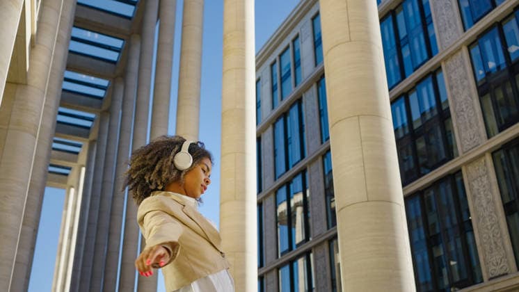 Mit Kopfhörern und einem strahlenden Lächeln tanzt eine junge berufstätige Frau frei in einem städtischen Raum With headphones on and a radiant smile, a young professional woman dances freely in an urban space, her dynamic movement contrasting with the static lines of the surrounding architecture. (License=RF) ,model released, Symbolfoto Copyright: xZoonar.com ElenaxShishkinax 23070160 ,model released, Symbolfoto ,property released