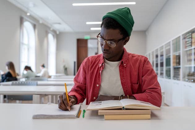 Talentierter junger afroamerikanischer Wissenschaftler mit Brille, der in der Bibliothek lernt. Bildungskonzept Talented young black guy scientist wearing glasses studying in library, reading book and taking notes. Focused African American male student writing research summary, sitting at desk. Education (License=RF) ,model released, Symbolfoto Copyright: xZoonar.com DmitriixMarchenkox xEnvatox 24618486 ,model released, Symbolfoto ,property released