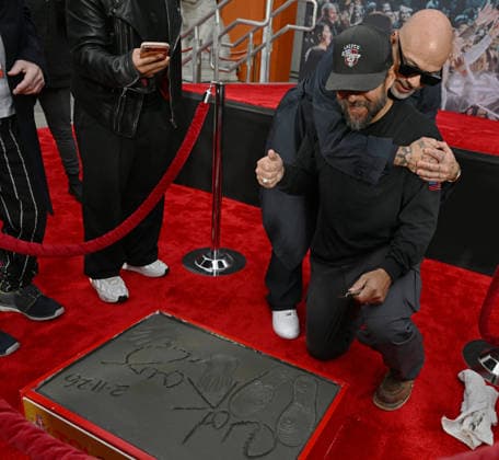Santos Resendiz (wearing hat) gets a hug from Jo Koy as Resendiz smooths out the cement surrounding Koy s hand and footprints at a ceremony honoring the comedian in the forecourt of the TCL Chinese Theatre in Los Angeles, California on Wednesday, February 11, 2026.  LAP20260211726 CHRISxCHEW