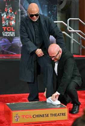Comedian and actor Jo Koy gets help with his shoe on the cement block as he is honored with a hand and footprint ceremony in the forecourt of the TCL Chinese Theatre in Los Angeles, California on Wednesday, February 11, 2026.  LAP20260211712 CHRISxCHEW