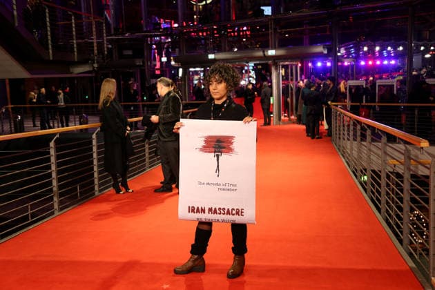 February 12, 2026, Berlin, Germany: A woman with the poster Iran Massacre poses on the red carpet at the opening ceremony of the 76th Berlin International Film Festival (Berlinale), which is Europe s first major film festival of the year, in Berlin. The festival runs from February 12 to 22, 2026. Berlin Germany - ZUMAf146 20260212_zip_f146_218 Copyright: xRouzbehxFouladix